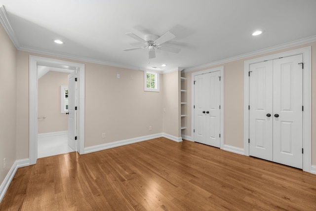 unfurnished bedroom featuring ornamental molding, light hardwood / wood-style floors, two closets, and ceiling fan