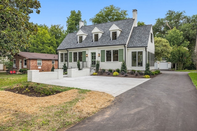 cape cod-style house featuring a garage and a front yard