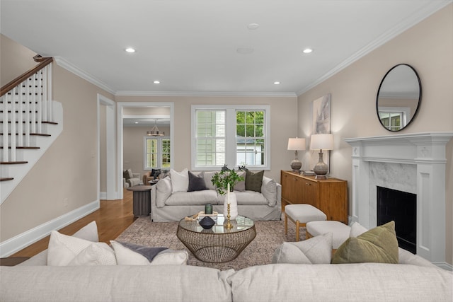 living room featuring light hardwood / wood-style floors, a high end fireplace, and crown molding