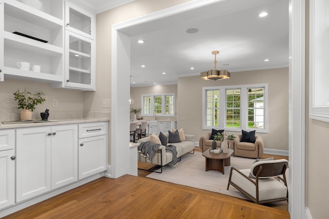 living room with light wood-type flooring, a wealth of natural light, and ornamental molding