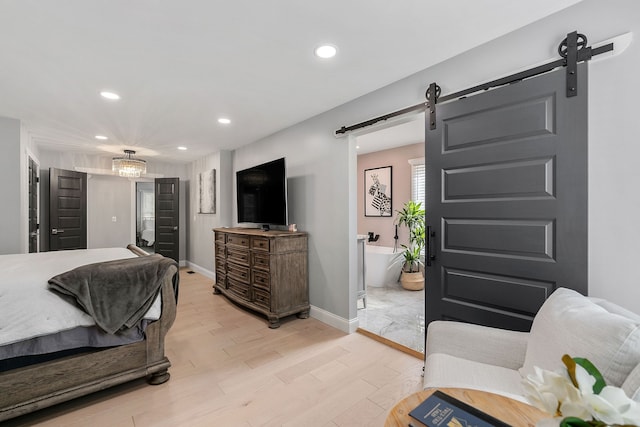 bedroom featuring a barn door and light hardwood / wood-style floors