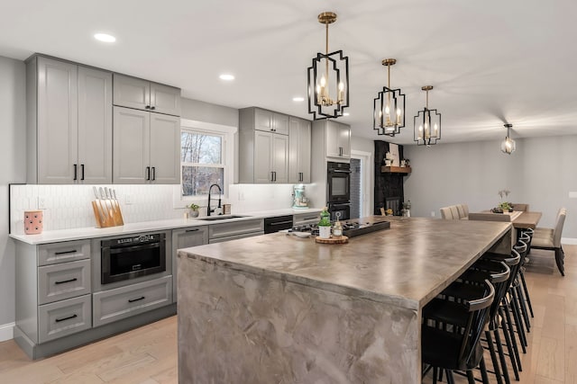 kitchen with light wood-type flooring, decorative light fixtures, sink, and a center island