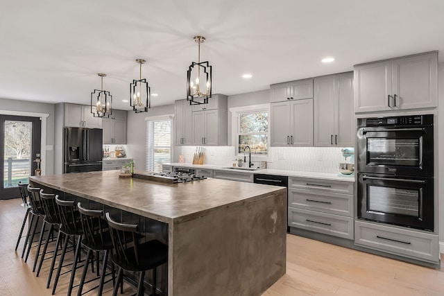 kitchen with refrigerator with ice dispenser, light hardwood / wood-style floors, a kitchen island, and plenty of natural light