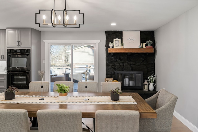 dining area featuring a notable chandelier, hardwood / wood-style flooring, and a fireplace