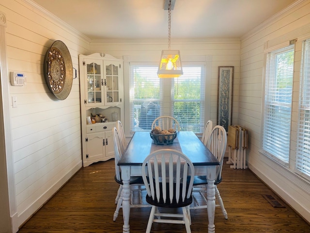 dining space with dark wood-type flooring and wood walls