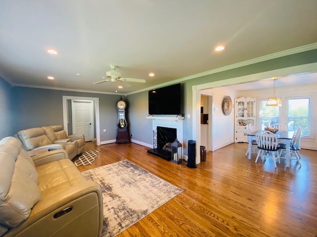 living room featuring ceiling fan, wood-type flooring, and ornamental molding