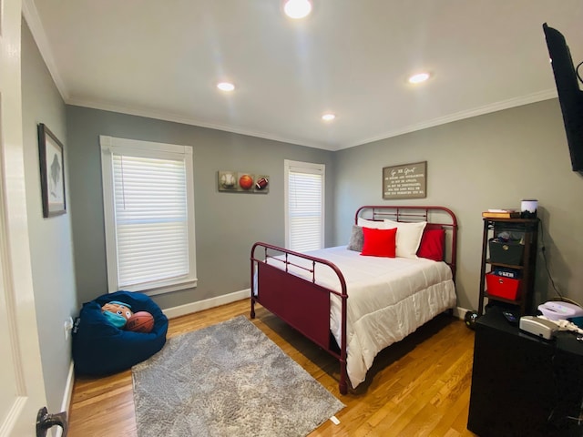 bedroom with wood-type flooring, multiple windows, and crown molding