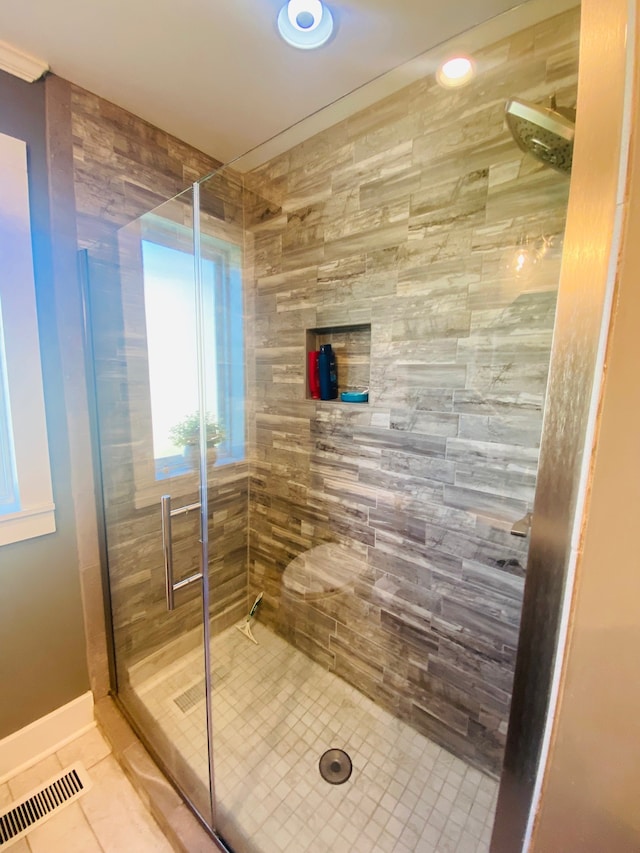 bathroom with a shower with door and tile patterned flooring