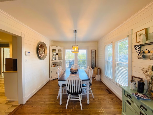 dining space featuring dark wood-type flooring, a wealth of natural light, radiator heating unit, and crown molding