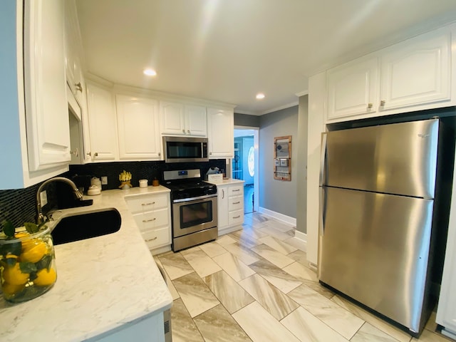 kitchen with stainless steel appliances, white cabinets, decorative backsplash, sink, and crown molding