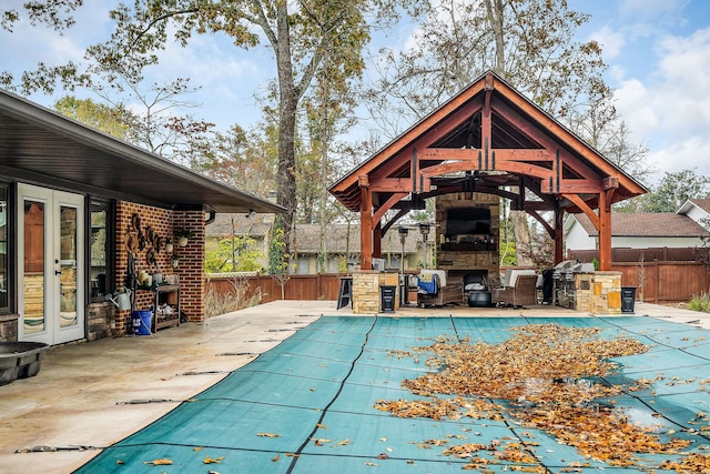 view of pool featuring an outdoor stone fireplace, a patio, an outdoor kitchen, and a gazebo