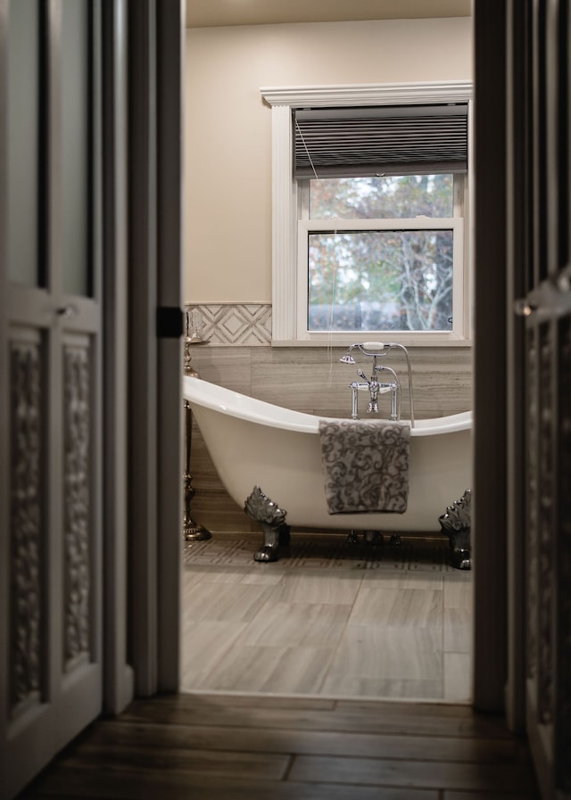 bathroom with a tub and tile walls