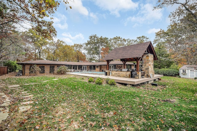 back of property featuring a deck, a storage unit, a lawn, and a gazebo