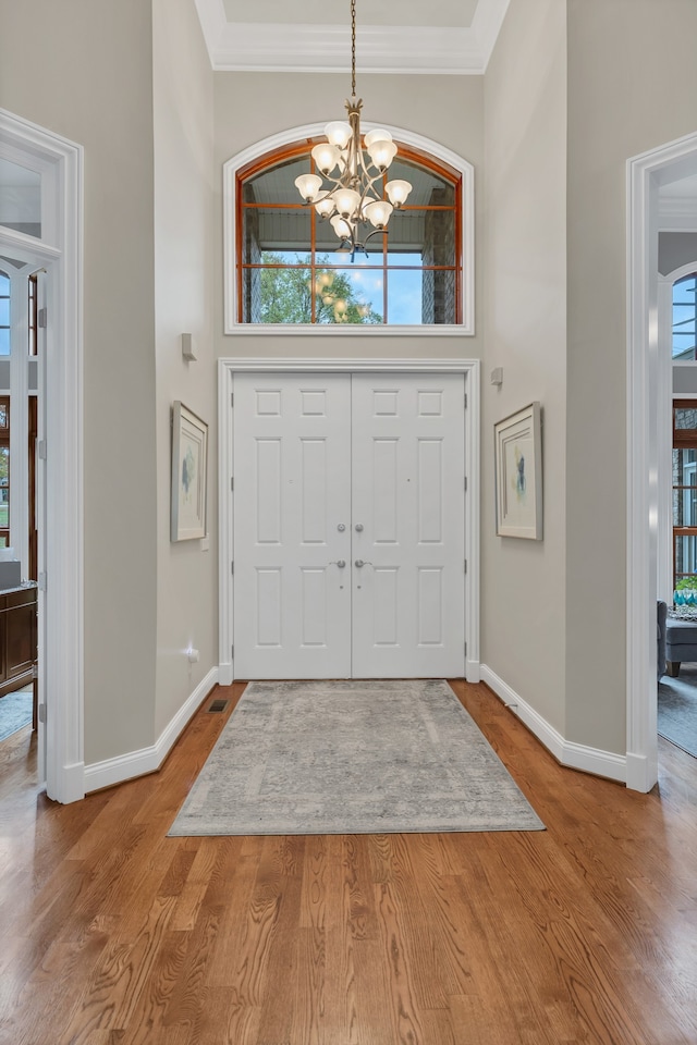 foyer featuring hardwood / wood-style floors, a notable chandelier, and crown molding