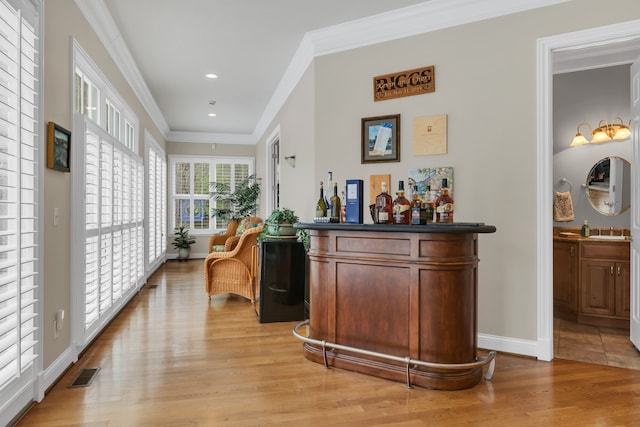 bar featuring light hardwood / wood-style floors, sink, and crown molding