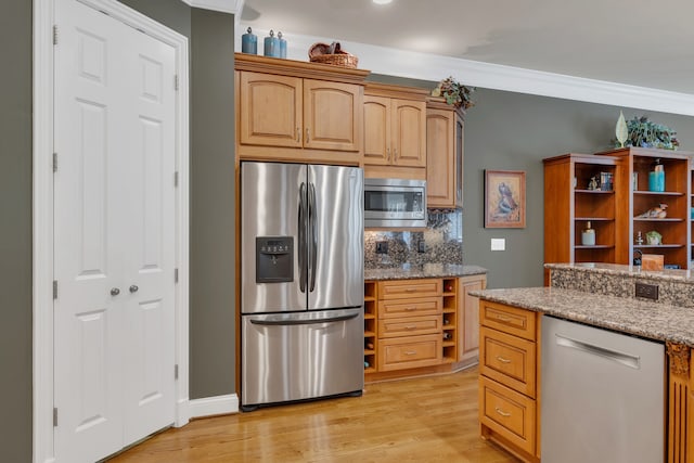 kitchen with light hardwood / wood-style floors, light stone counters, decorative backsplash, crown molding, and appliances with stainless steel finishes