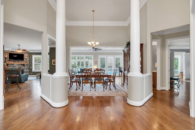 dining room with wood-type flooring, ornate columns, and ceiling fan with notable chandelier