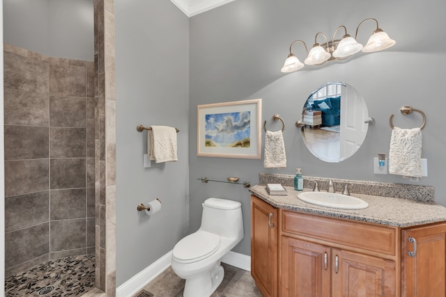 bathroom with toilet, tile patterned flooring, a tile shower, ornamental molding, and vanity