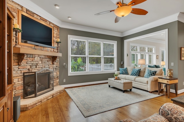 living room featuring a wealth of natural light, wood-type flooring, ornamental molding, and a fireplace