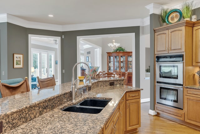 kitchen with light hardwood / wood-style floors, sink, stainless steel double oven, crown molding, and light stone countertops