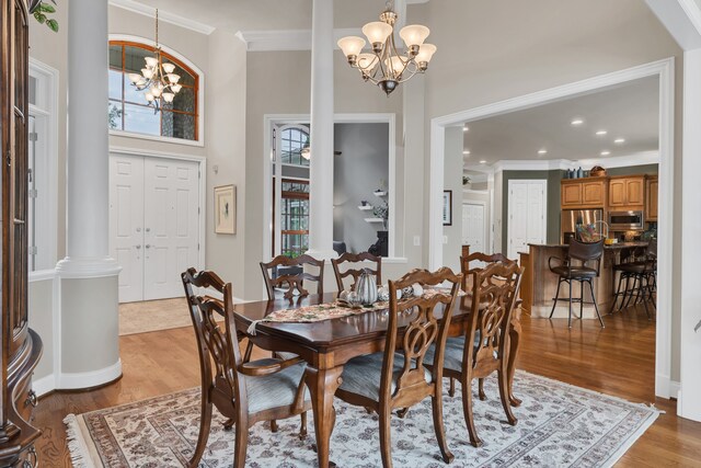 dining area with light hardwood / wood-style flooring, a notable chandelier, and decorative columns