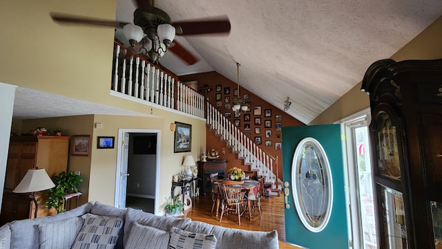 living room featuring hardwood / wood-style floors, ceiling fan, a textured ceiling, and vaulted ceiling