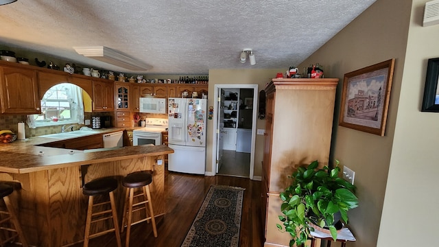 kitchen with white appliances, decorative backsplash, a kitchen breakfast bar, dark wood-type flooring, and kitchen peninsula