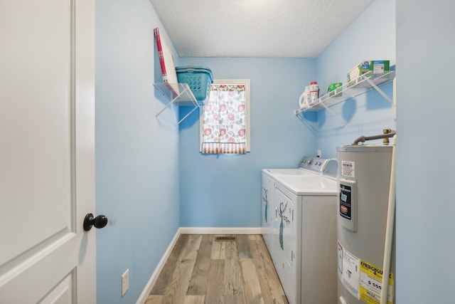 laundry room featuring washing machine and clothes dryer, electric water heater, light hardwood / wood-style floors, and a textured ceiling