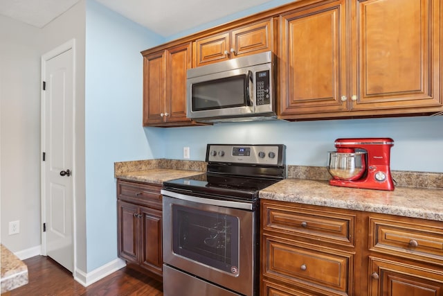 kitchen with dark hardwood / wood-style flooring and appliances with stainless steel finishes