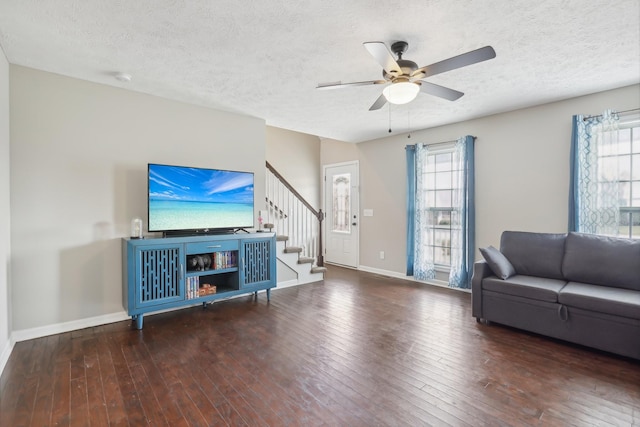 living room featuring a wealth of natural light, ceiling fan, dark wood-type flooring, and a textured ceiling