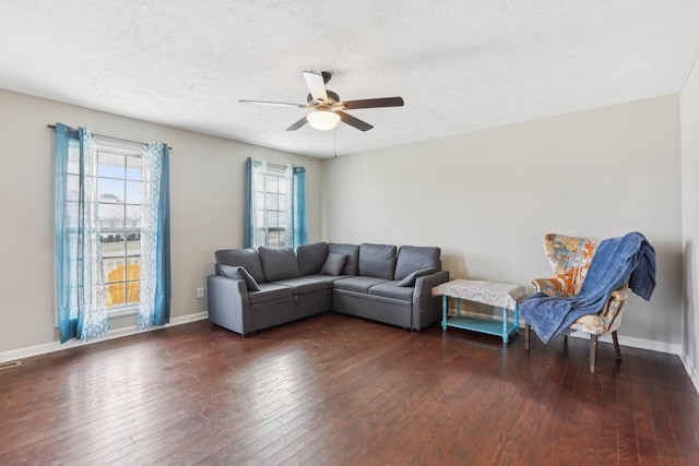 living room featuring ceiling fan, dark wood-type flooring, and a textured ceiling