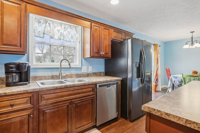 kitchen with an inviting chandelier, sink, hardwood / wood-style flooring, appliances with stainless steel finishes, and decorative light fixtures