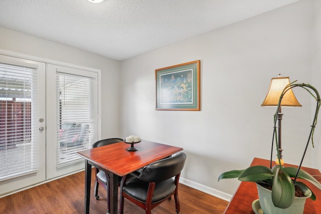 dining area with hardwood / wood-style floors, a textured ceiling, and french doors