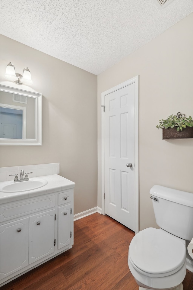 bathroom with hardwood / wood-style floors, toilet, vanity, and a textured ceiling