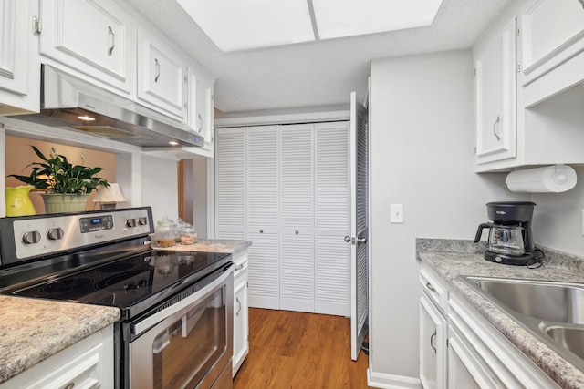 kitchen featuring sink, white cabinets, stainless steel range with electric stovetop, and light wood-type flooring