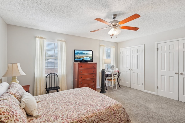 bedroom with ceiling fan, carpet, a textured ceiling, and multiple closets