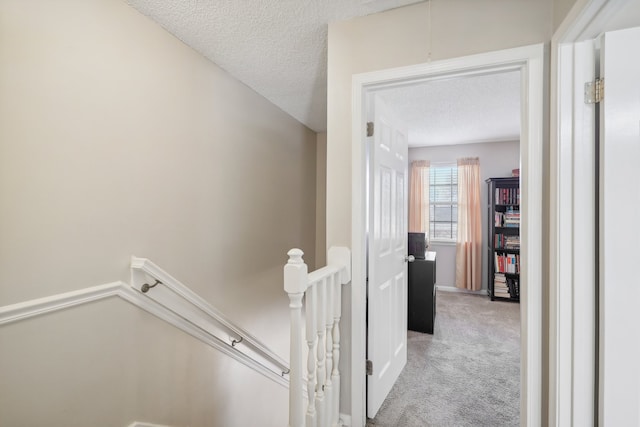 hall featuring light colored carpet and a textured ceiling