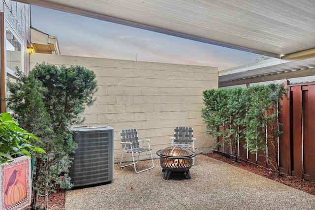 patio terrace at dusk featuring central air condition unit and an outdoor fire pit