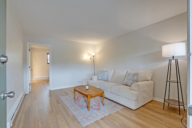 living room with a textured ceiling, light hardwood / wood-style flooring, and a baseboard heating unit