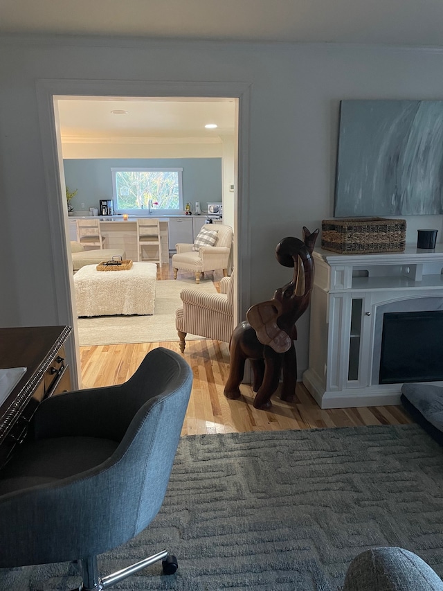 living room featuring hardwood / wood-style flooring, ornamental molding, and a fireplace