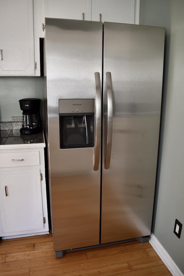 kitchen featuring white cabinets, light hardwood / wood-style flooring, and stainless steel fridge