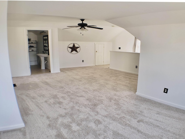 unfurnished living room featuring sink, vaulted ceiling, light carpet, and ceiling fan