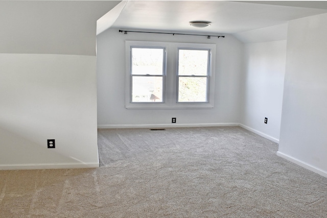 additional living space featuring light colored carpet and lofted ceiling