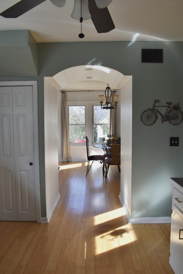 hallway featuring light wood-type flooring and an inviting chandelier