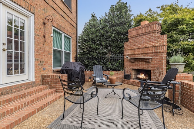 view of patio featuring an outdoor brick fireplace and grilling area