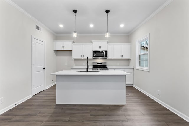 kitchen with appliances with stainless steel finishes, white cabinetry, sink, pendant lighting, and an island with sink