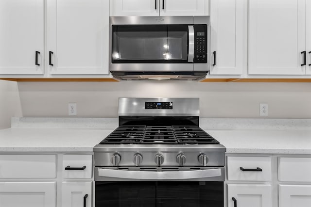 kitchen with light stone counters, white cabinetry, and stainless steel appliances