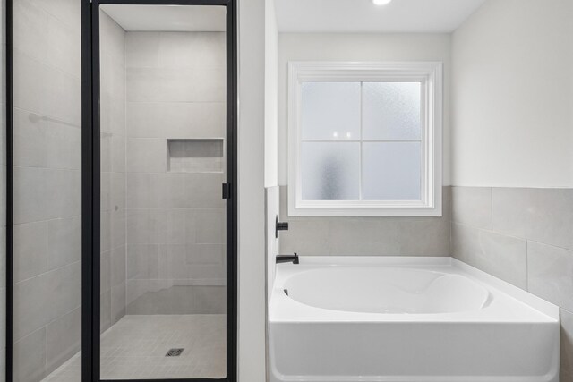 bathroom featuring tile walls and plus walk in shower