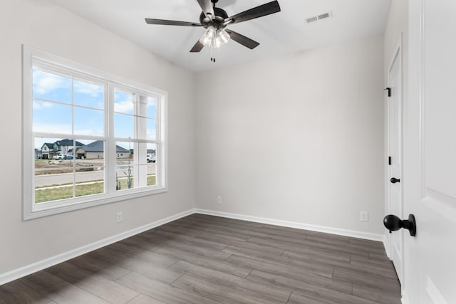 unfurnished room featuring ceiling fan, dark wood-type flooring, and a wealth of natural light