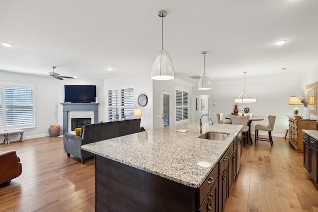 kitchen featuring pendant lighting, light hardwood / wood-style floors, a kitchen island with sink, and sink